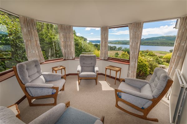 sunroom with lots of windows and view of bushes and water